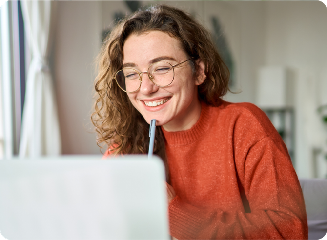 A woman is smiling while looking at a laptop computer.